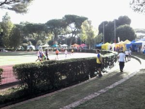 La pista con gli atleti in gara e nello sfondo alcuni degli Stand dei vari sponsor